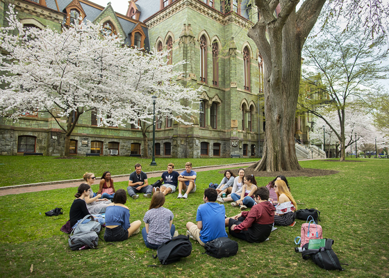 A group of students sitting in a Circle outside in front of College Hall